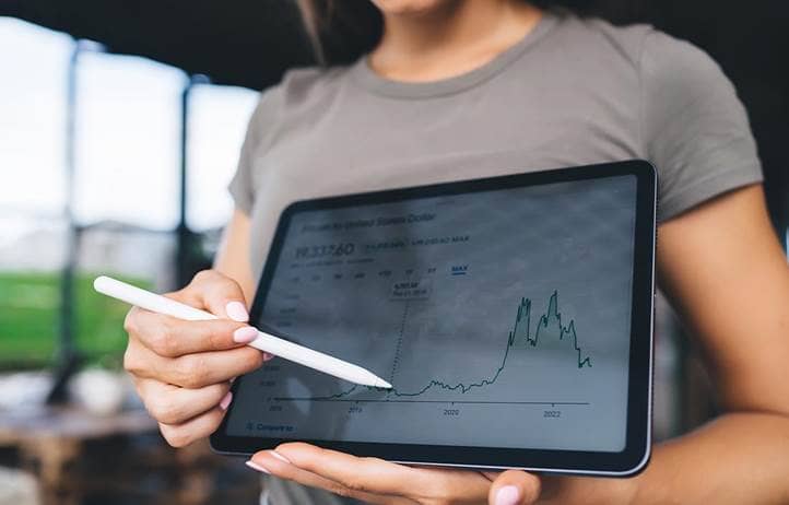 Woman holding a tablet pointing to a chart.