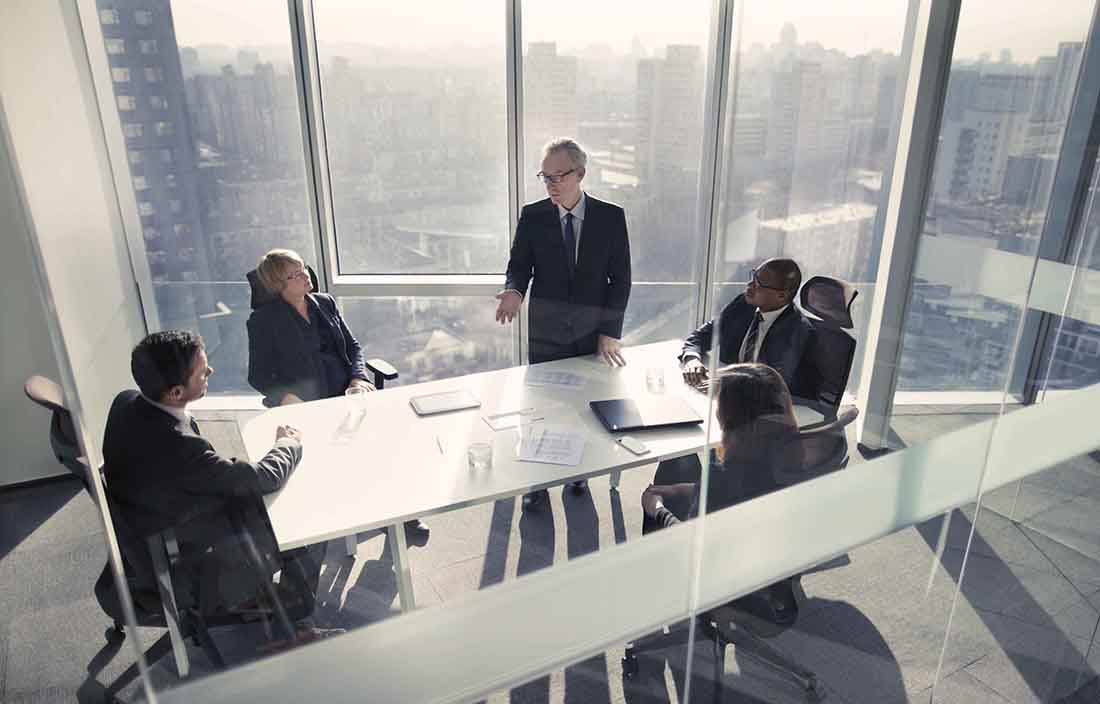 People sitting and standing around a conference room table