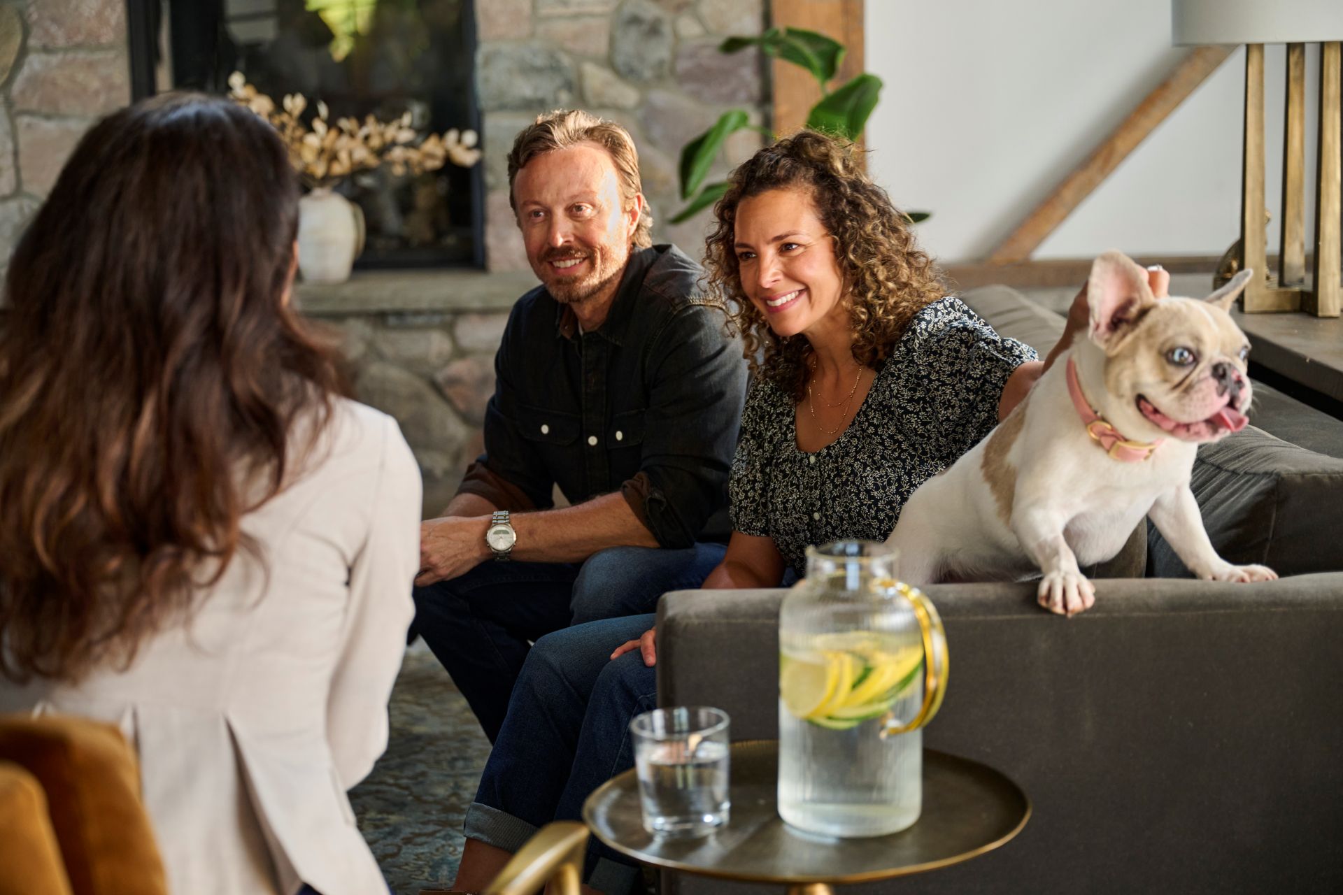 Couple and their dog sitting on a couch and talking with their Plante Moran Wealth Management advisor.