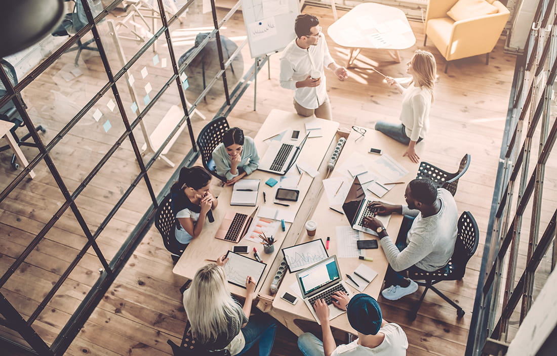 Group of people working together at desks on laptops