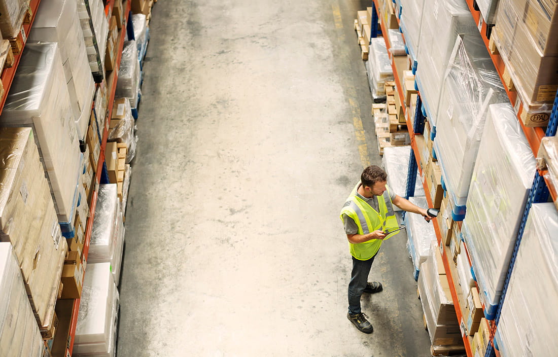 Warehouse worker checking inventory on warehouse shelves.