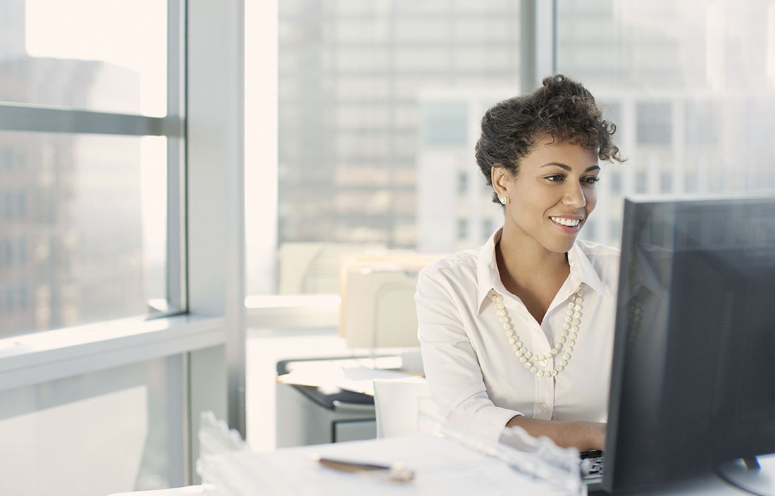 Young business woman sitting in her office using her desktop computer.