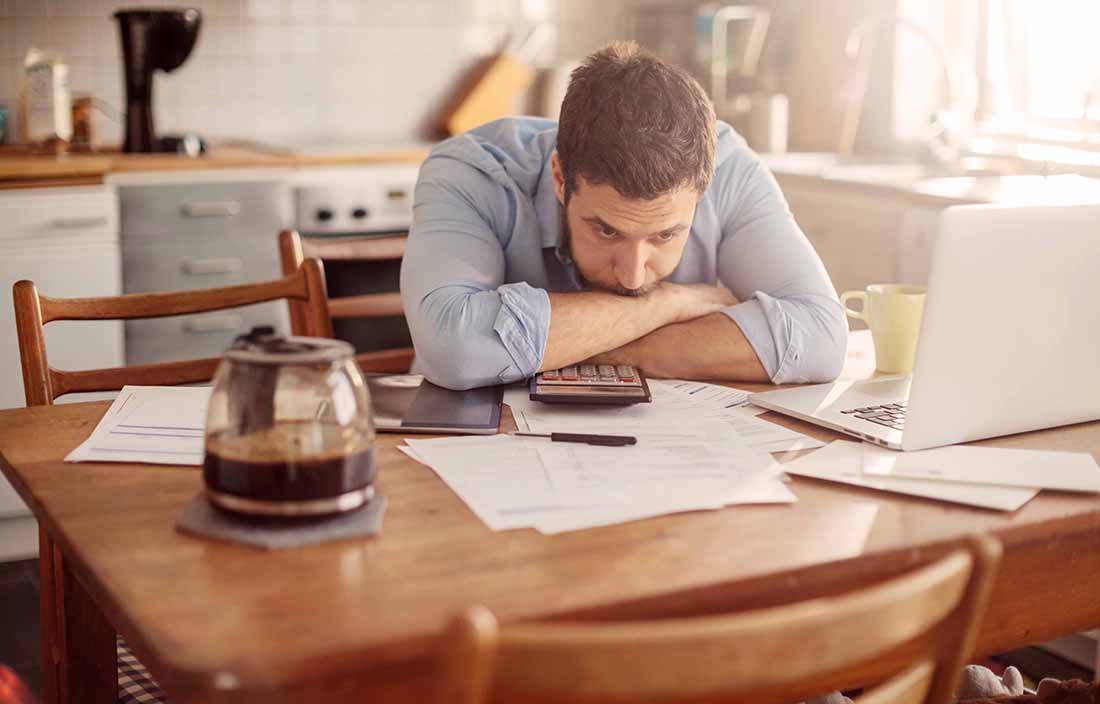 A frustrated employee working from home with his head down on the desk.