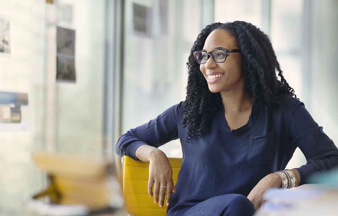 Businesswoman sitting at a conference table smiling looking out the window.