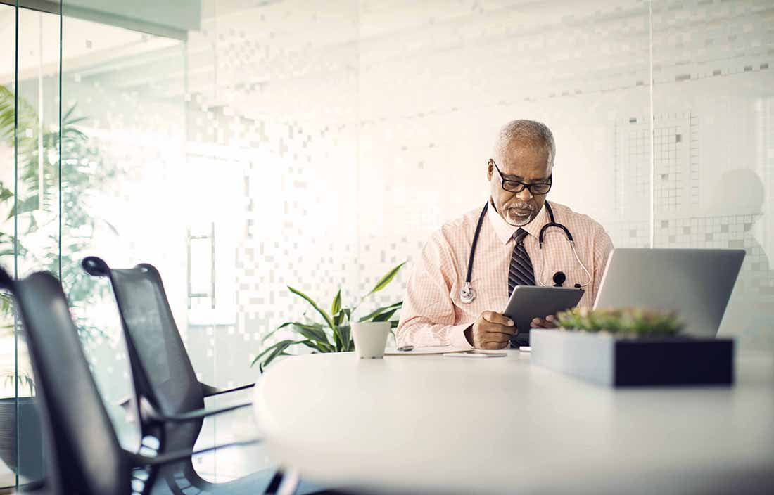 Healthcare professional reviewing information on a tablet.