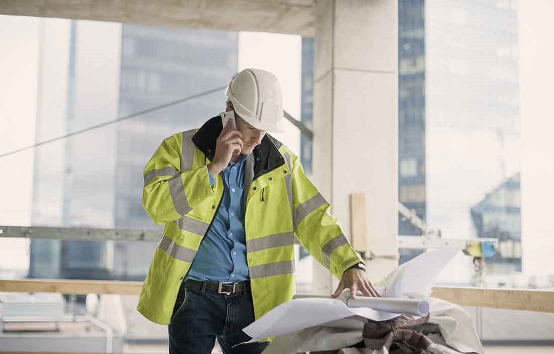 Construction worker in a hard hat viewing blueprints and planning documents.