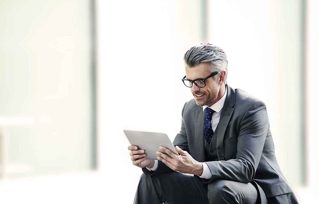 Businessman reading news on a tablet handheld device.