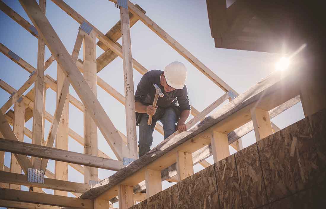 Construction worker working on a roofing segment of a house.