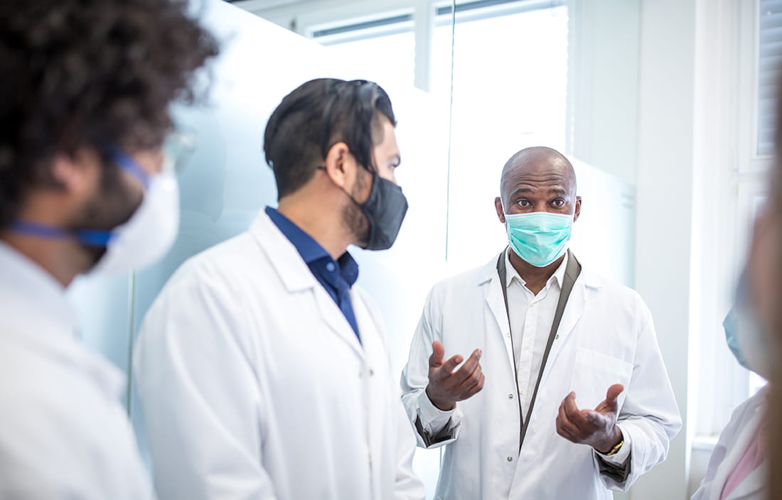 Doctors discussing while wearing protective facemasks.