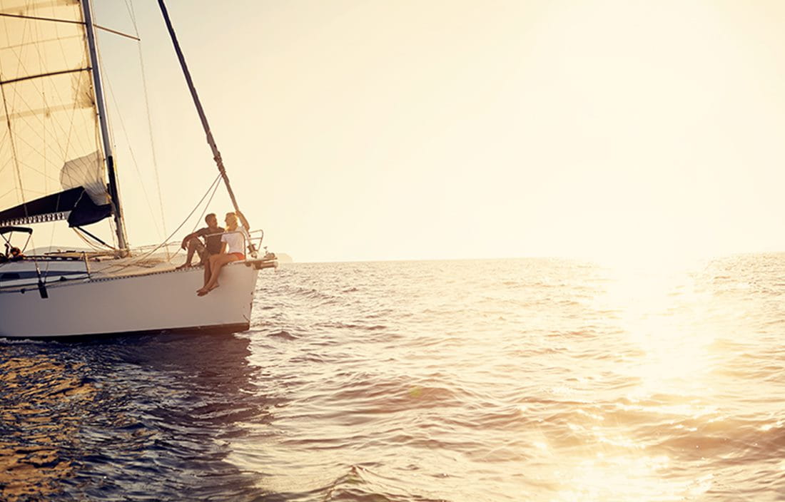 Couple on a sailboat sailing ocean waters.
