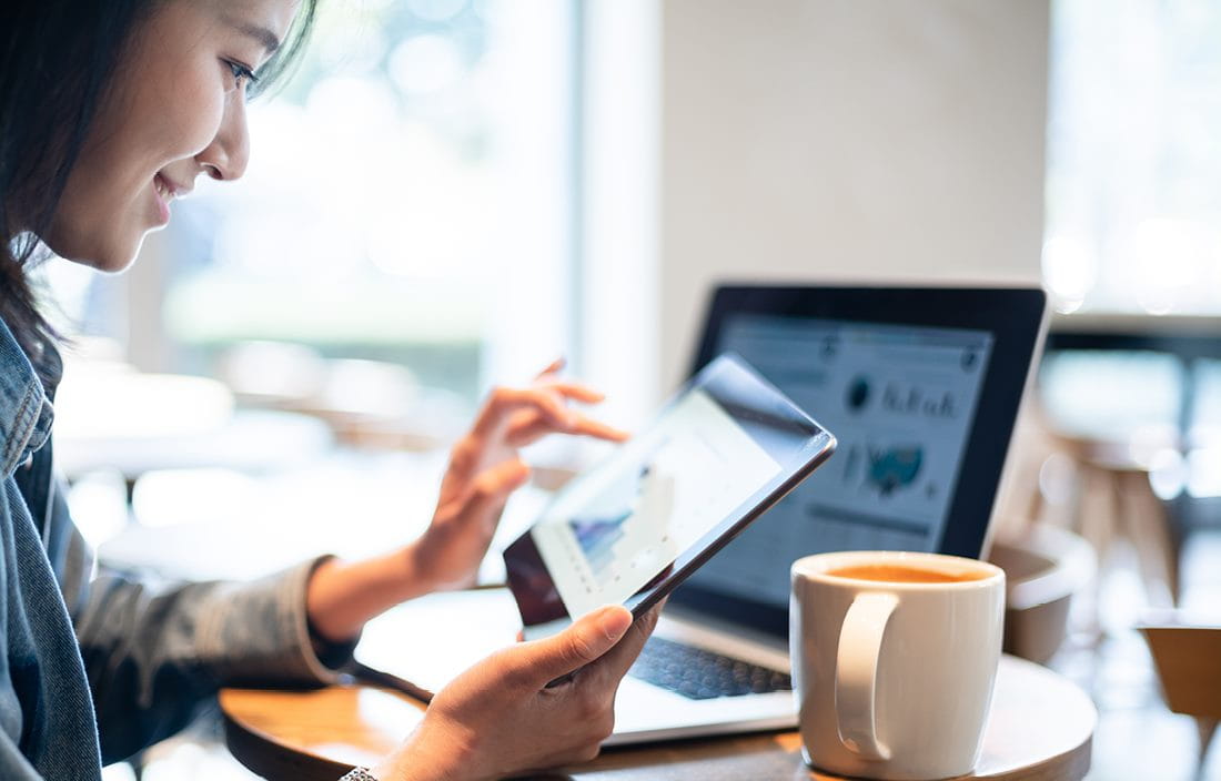 Business professional using a tablet while sitting in a coffee shop.