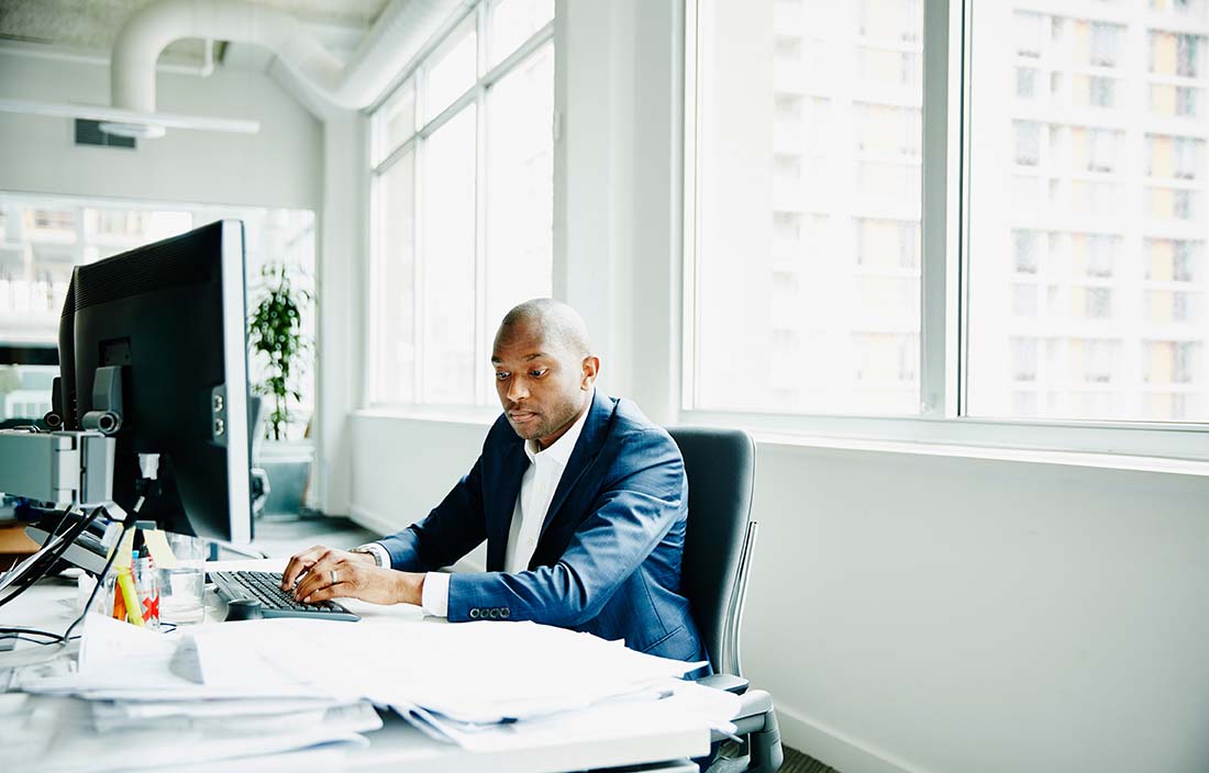 Businessperson sitting at his desktop computer typing.