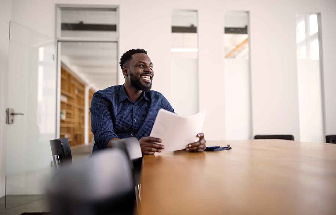 Business professional sitting at a conference table holding papers.