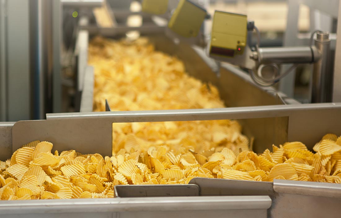 Close-up view of potato chips on a conveyor belt.