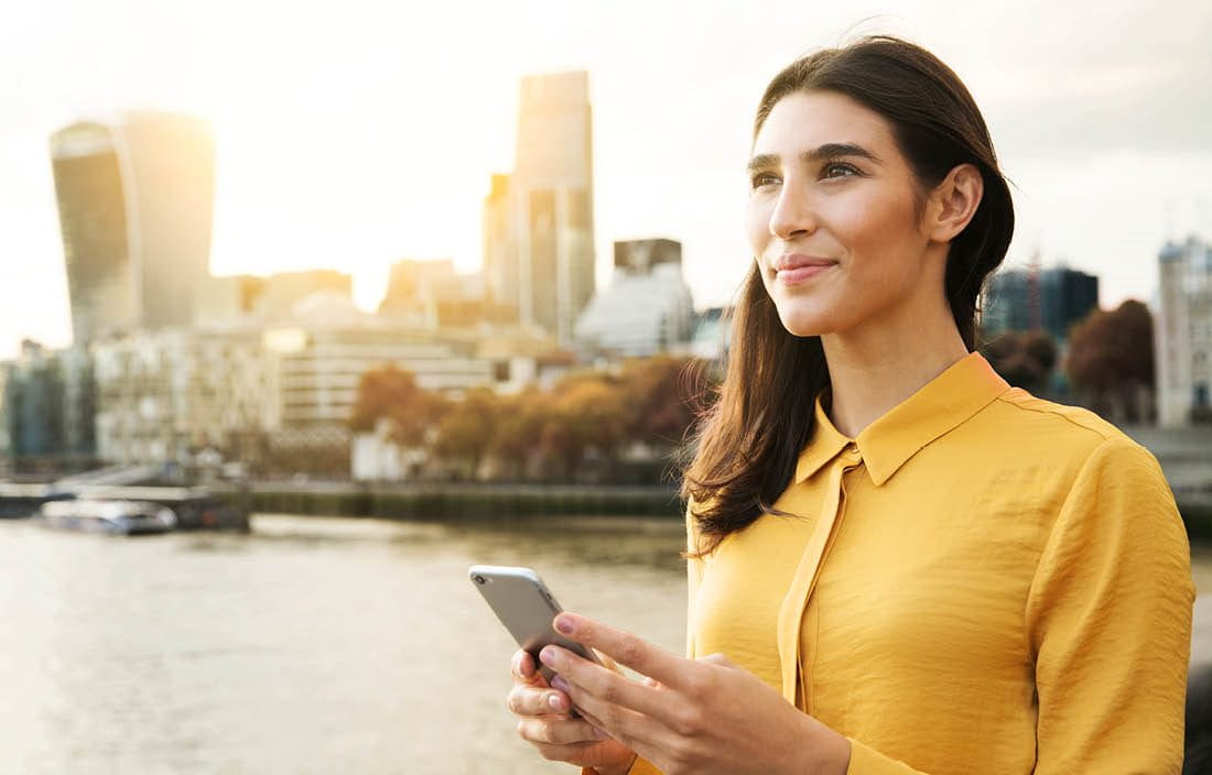 Business person holding a cell phone with a sunset in the background.