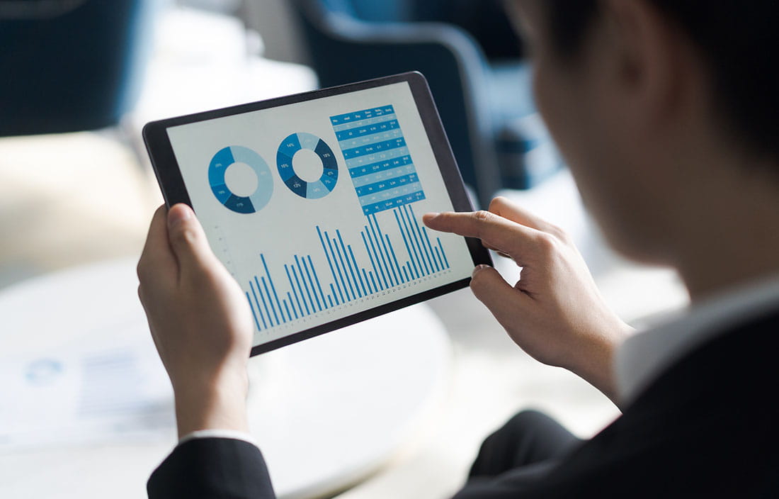 A close-up photo/view of a staff member holding a tablet device.