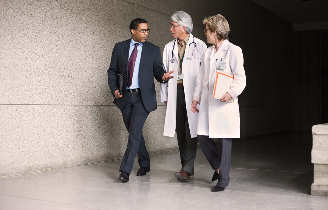 A business professional walking with two doctors down a hallway.