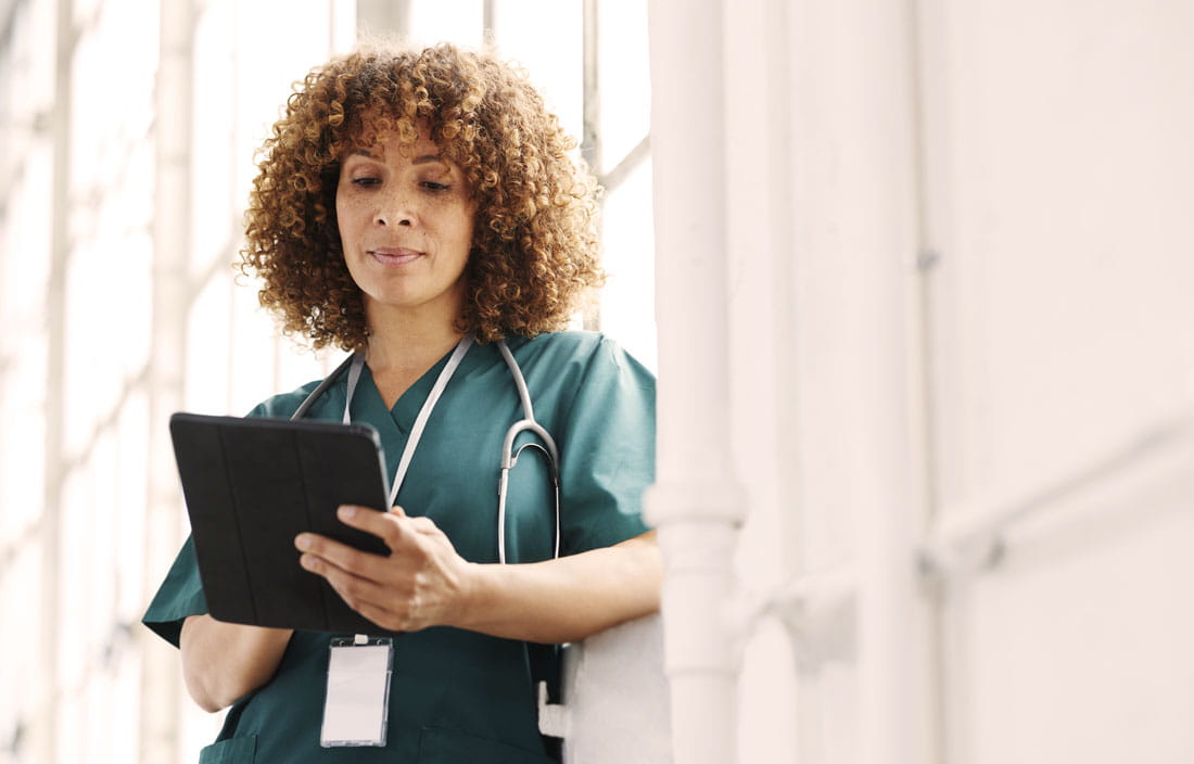 Doctor wearing a green uniform using a tablet handheld device.