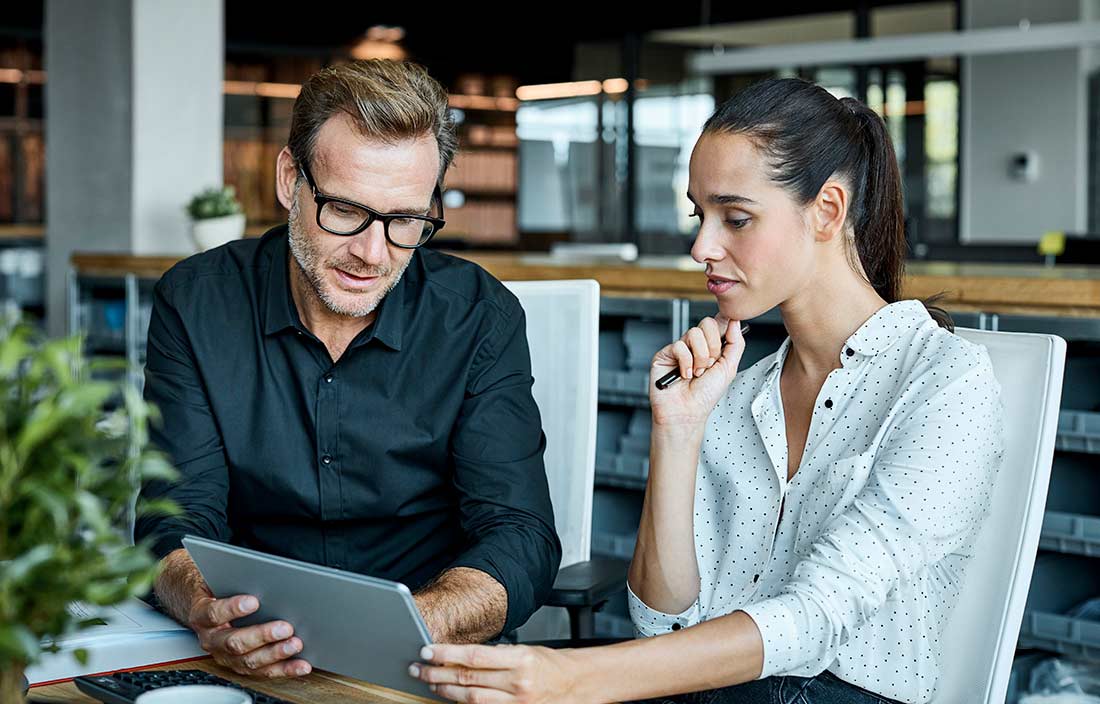 Two business professionals reviewing information together on a tablet device. 