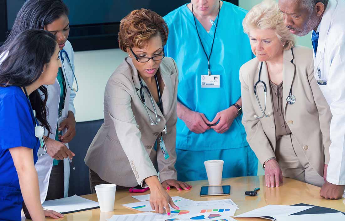 Doctors and nurses reviewing information on a table top.