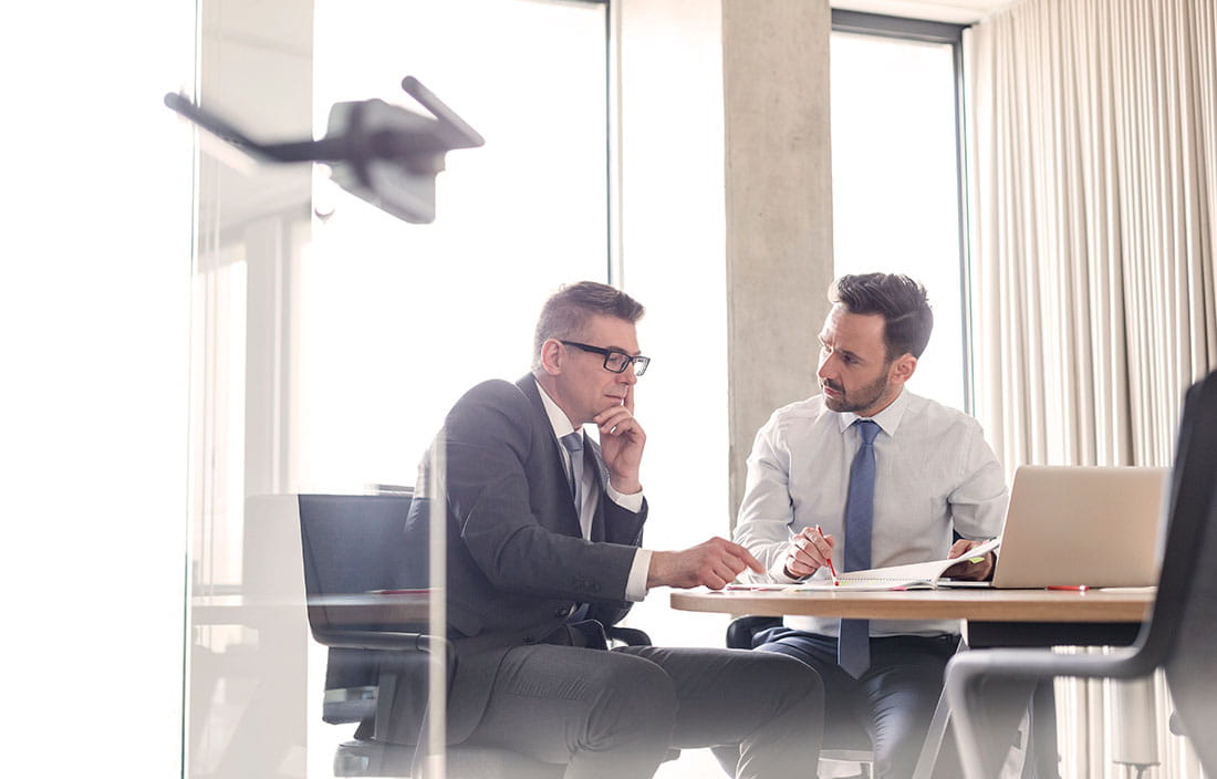 Two businessmen sitting at a table talking.